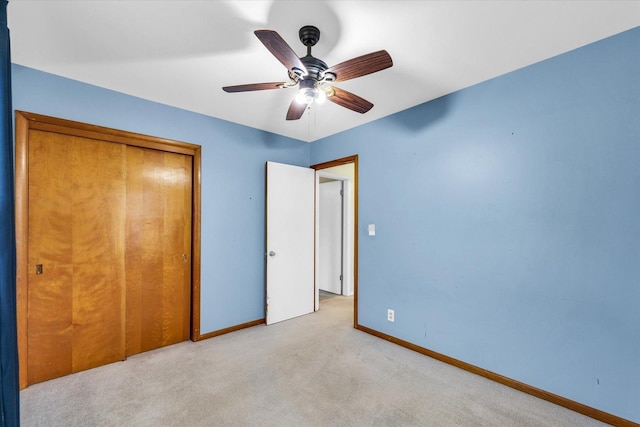 unfurnished bedroom featuring ceiling fan, light carpet, and a closet