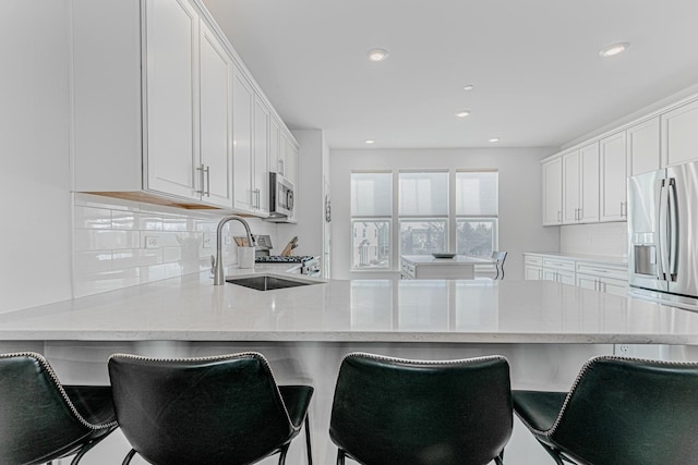 kitchen with appliances with stainless steel finishes, white cabinets, backsplash, and kitchen peninsula