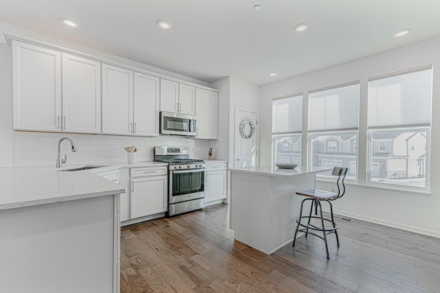 kitchen featuring a kitchen island, appliances with stainless steel finishes, sink, and white cabinets