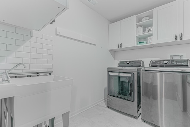 clothes washing area with cabinets, sink, and washing machine and dryer