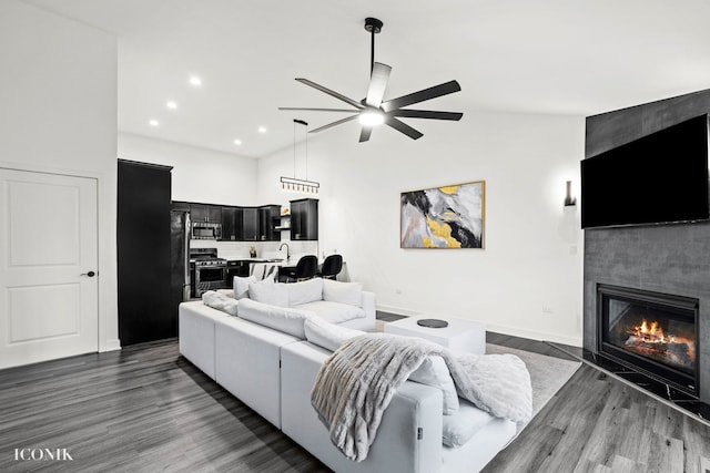 living room featuring a fireplace, high vaulted ceiling, ceiling fan, and dark wood-type flooring