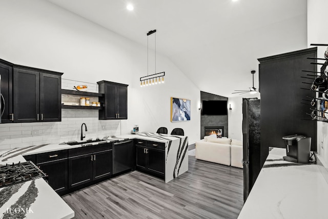 kitchen featuring sink, stainless steel dishwasher, light wood-type flooring, tasteful backsplash, and decorative light fixtures