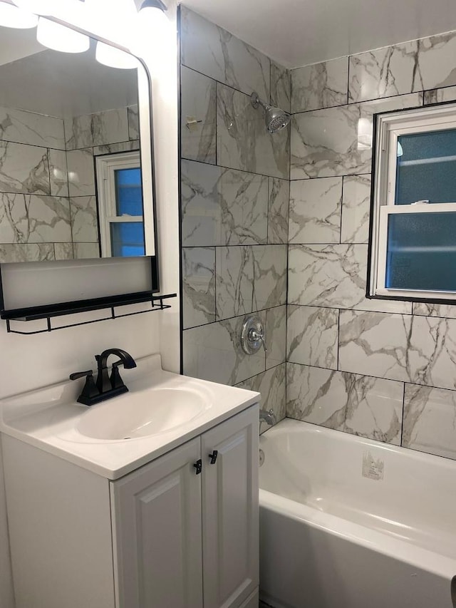 bathroom with tiled shower / bath combo and vanity