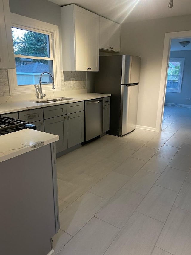 kitchen featuring decorative backsplash, stainless steel appliances, a healthy amount of sunlight, and sink