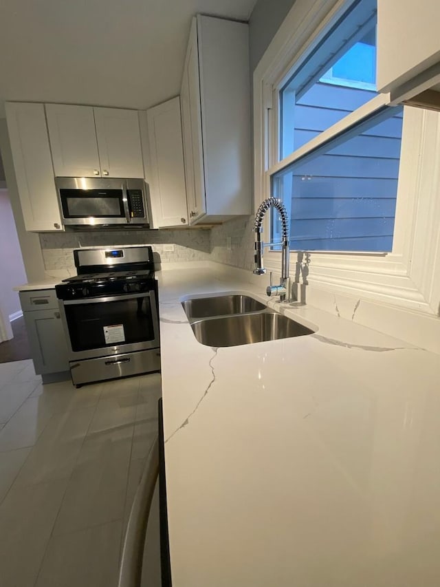 kitchen with appliances with stainless steel finishes, white cabinetry, tile patterned floors, and sink