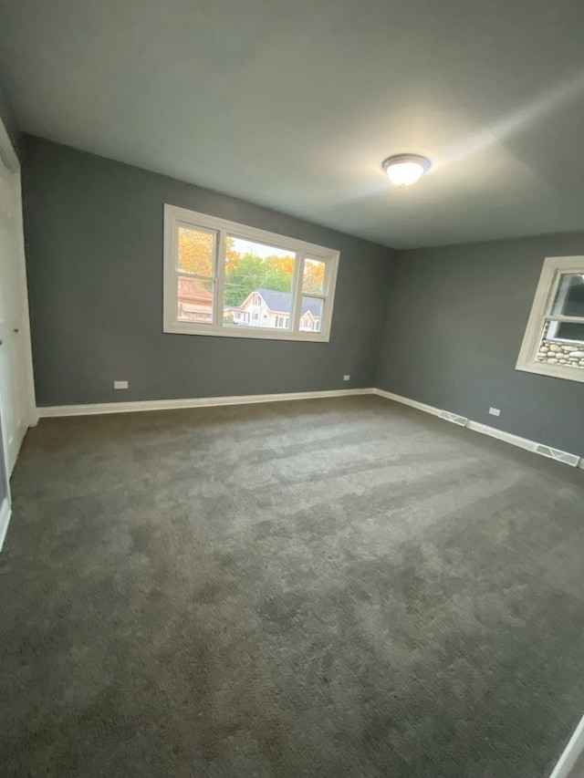 unfurnished room featuring dark colored carpet