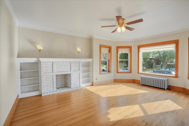 unfurnished living room with radiator, ceiling fan, ornamental molding, a fireplace, and light hardwood / wood-style floors