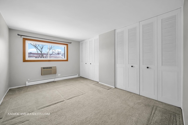 unfurnished bedroom with light carpet, an AC wall unit, baseboard heating, and multiple closets