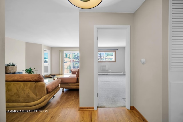 hallway with a wall mounted air conditioner, wood-type flooring, and a baseboard heating unit