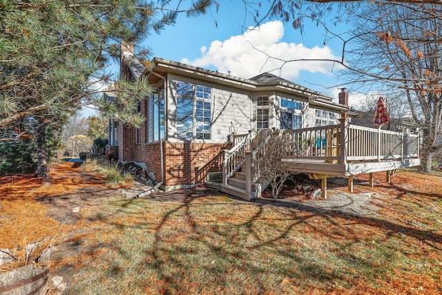 back of property with a deck and a lawn