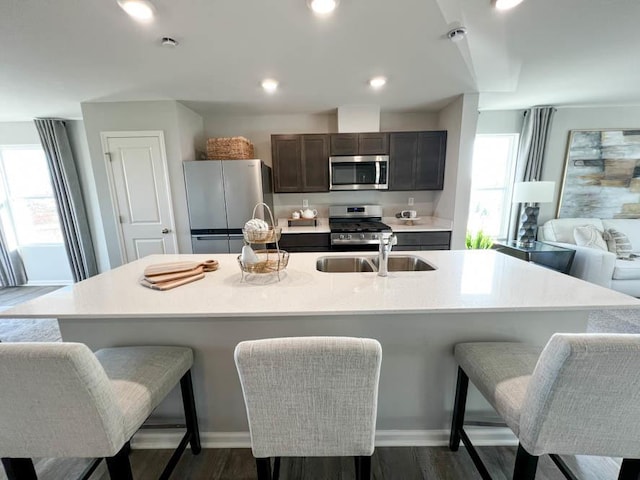 kitchen with a center island with sink, dark hardwood / wood-style floors, sink, and appliances with stainless steel finishes