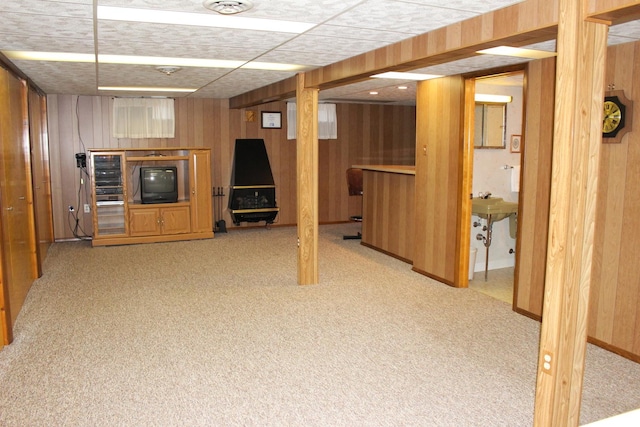 basement with light carpet and wood walls