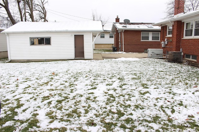 snow covered house featuring cooling unit