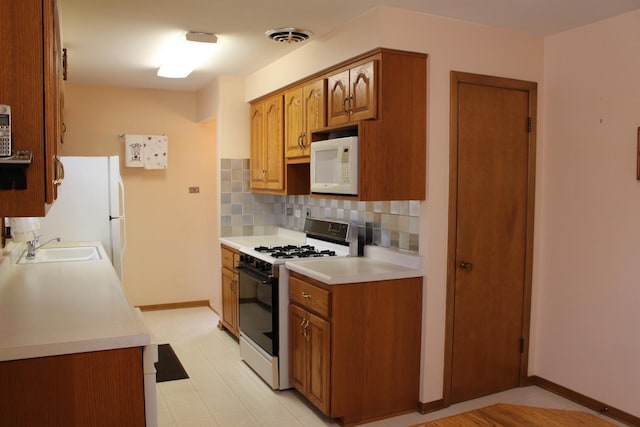 kitchen featuring white appliances, sink, and backsplash