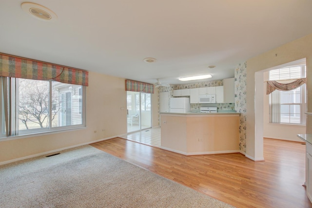 kitchen featuring white cabinetry, white appliances, kitchen peninsula, and light wood-type flooring