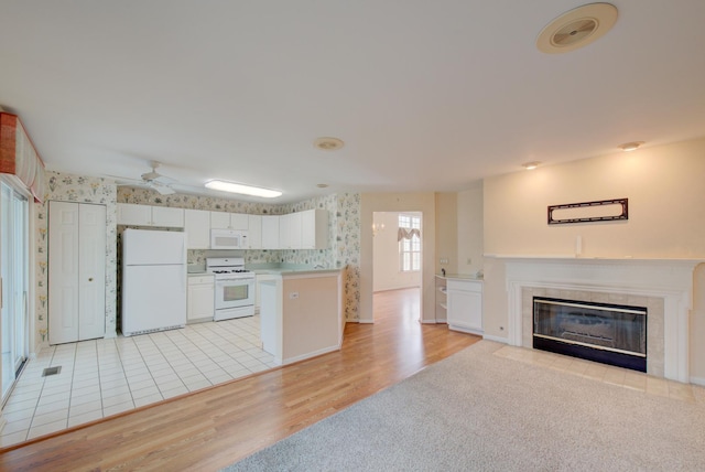 kitchen with white cabinetry, white appliances, a fireplace, and light wood-type flooring