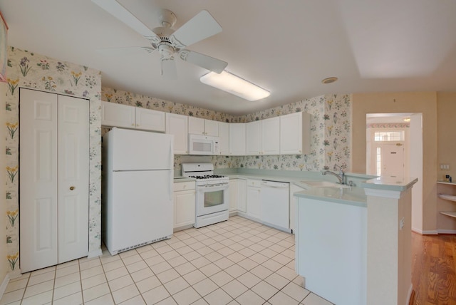 kitchen featuring sink, white cabinetry, light tile patterned floors, kitchen peninsula, and white appliances