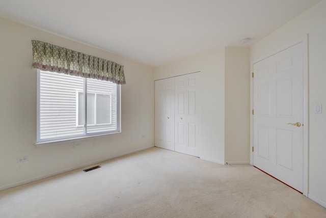 unfurnished bedroom with a closet and light carpet