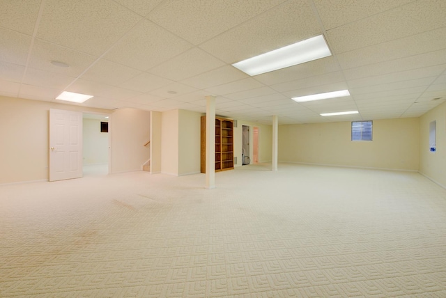 basement featuring a paneled ceiling and light carpet