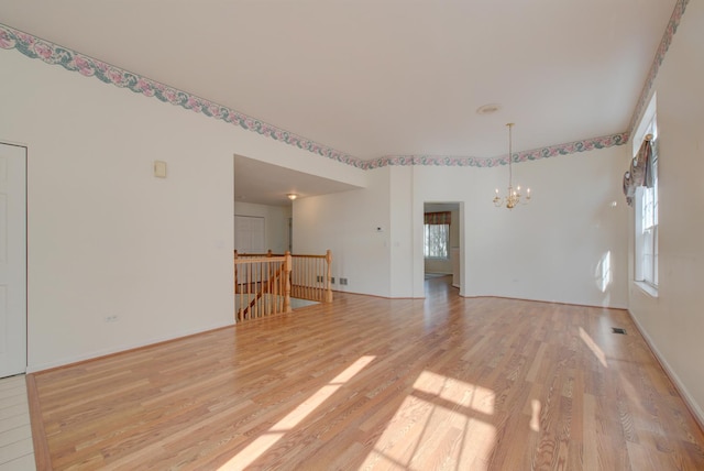 spare room featuring an inviting chandelier and light hardwood / wood-style flooring