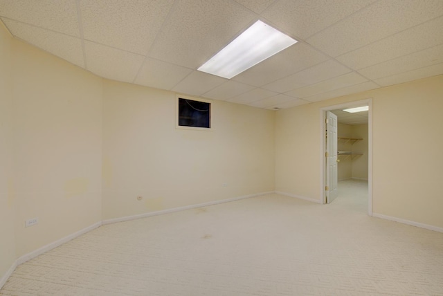 basement featuring a paneled ceiling and light carpet