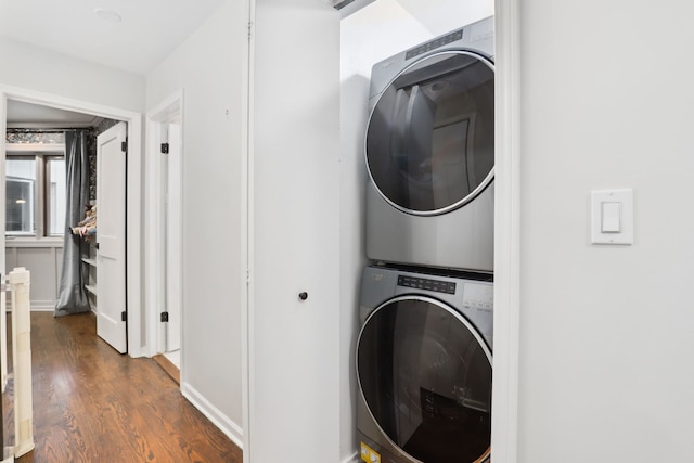 laundry area featuring stacked washer and dryer and dark wood-type flooring