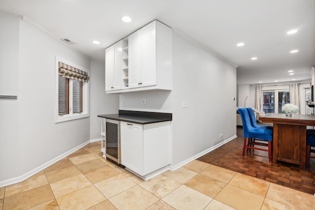 kitchen with white cabinetry, crown molding, light parquet flooring, and beverage cooler