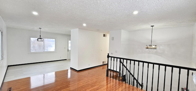 hall with light wood-type flooring and a textured ceiling