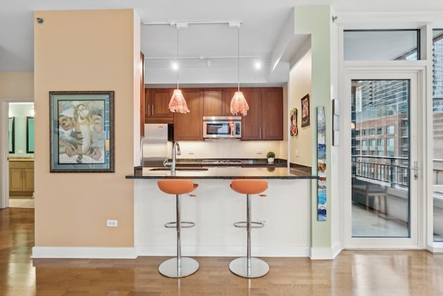 kitchen featuring track lighting, a breakfast bar, stainless steel appliances, sink, and pendant lighting