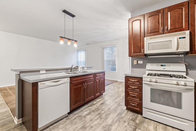 kitchen featuring sink, decorative light fixtures, white appliances, a kitchen island, and light wood-type flooring