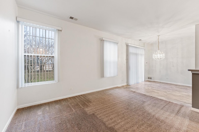 carpeted empty room with an inviting chandelier