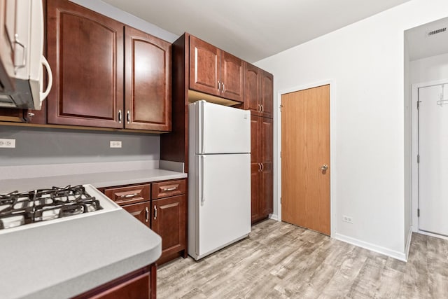 kitchen with white appliances and light hardwood / wood-style flooring