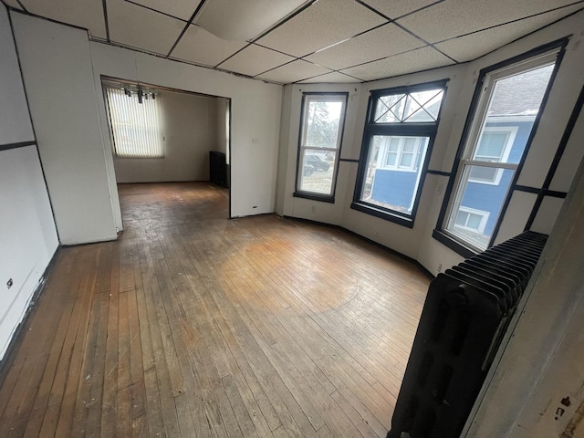 empty room featuring a paneled ceiling, an inviting chandelier, and hardwood / wood-style flooring