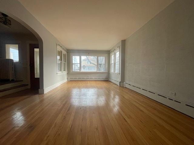 unfurnished room featuring light hardwood / wood-style flooring, radiator, and a baseboard radiator