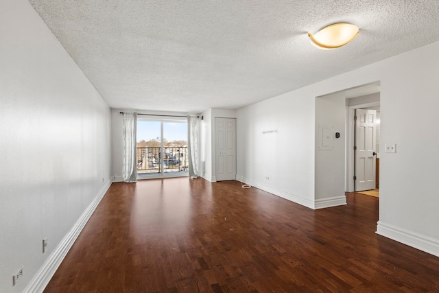 spare room featuring dark hardwood / wood-style flooring and a textured ceiling