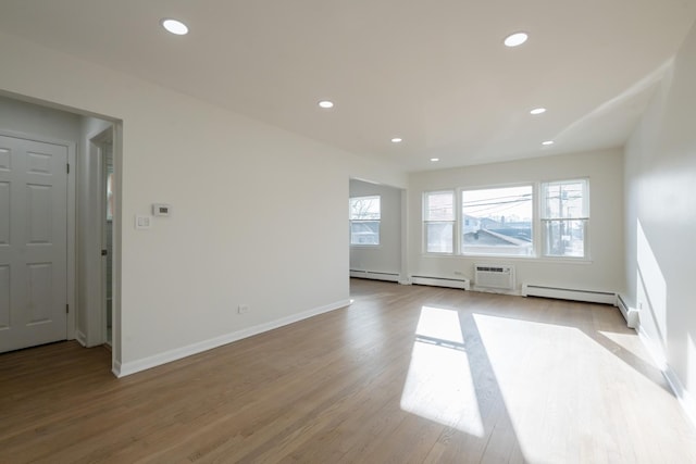 spare room featuring a wall mounted air conditioner, plenty of natural light, light hardwood / wood-style floors, and baseboard heating