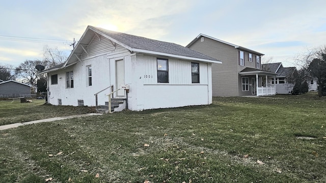 view of front of property with entry steps, roof with shingles, and a front yard