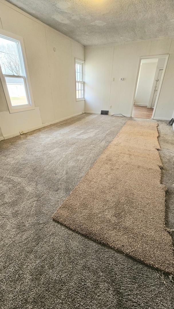 carpeted empty room featuring a textured ceiling