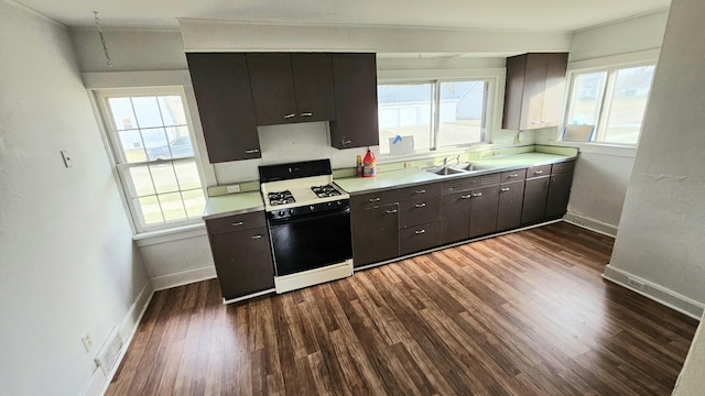 kitchen featuring light countertops, dark wood-style flooring, a sink, and range with gas cooktop