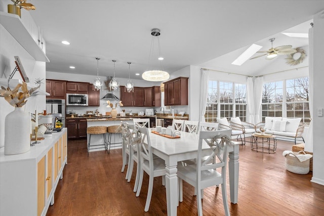 dining room with ceiling fan, dark hardwood / wood-style flooring, and lofted ceiling with skylight