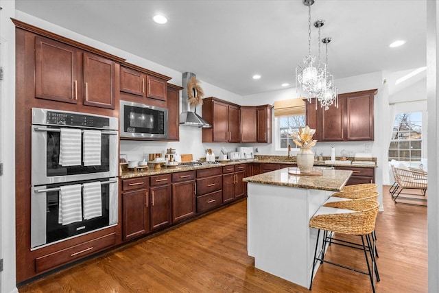 kitchen featuring a kitchen bar, appliances with stainless steel finishes, pendant lighting, a center island, and dark hardwood / wood-style floors