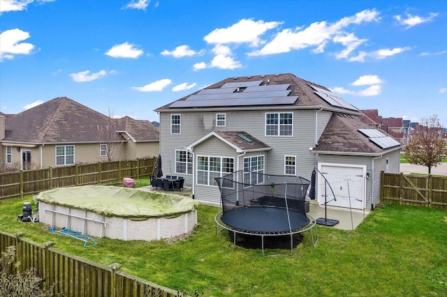 back of property with solar panels, a yard, and a trampoline