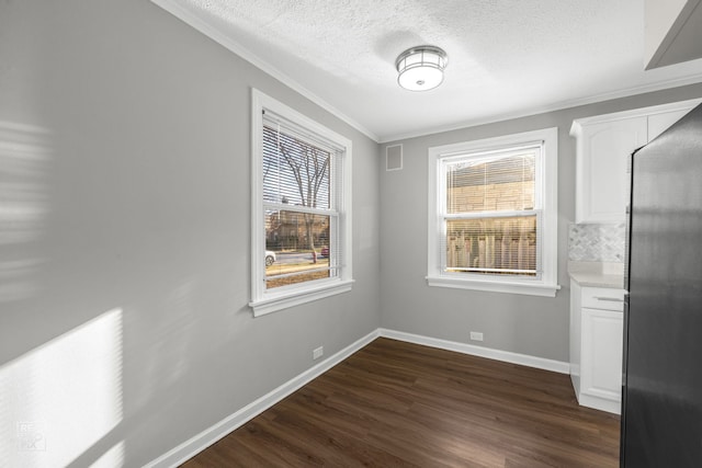 unfurnished dining area with a wealth of natural light, crown molding, dark wood-type flooring, and a textured ceiling