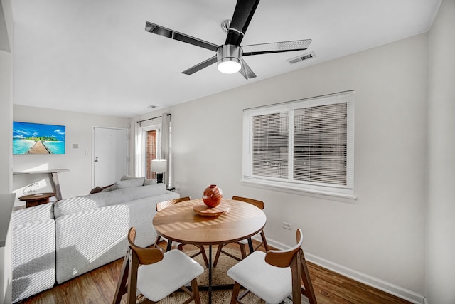 dining space with ceiling fan and dark wood-type flooring