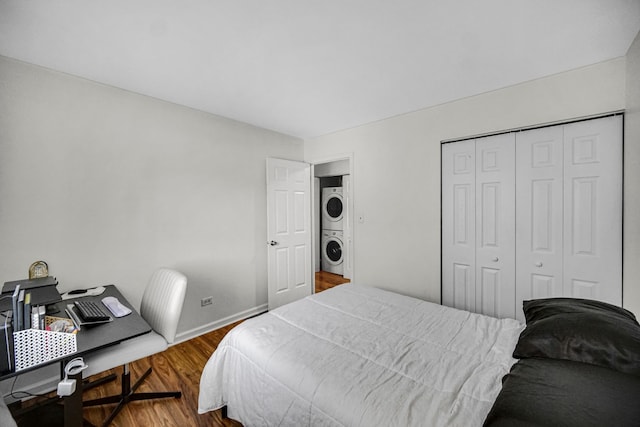 bedroom with hardwood / wood-style floors, a closet, and stacked washer and clothes dryer