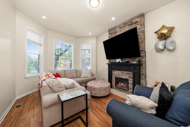 living room featuring a stone fireplace and wood-type flooring