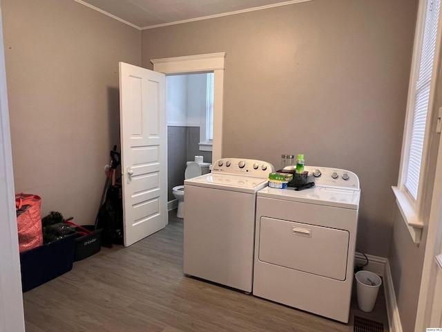 clothes washing area with hardwood / wood-style flooring, crown molding, and independent washer and dryer