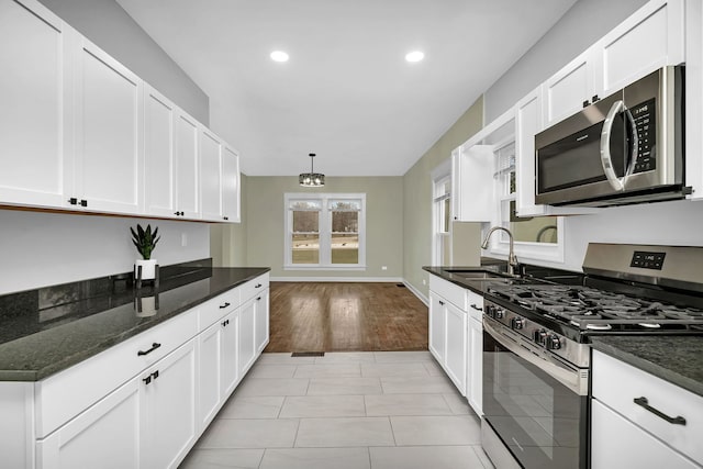 kitchen featuring appliances with stainless steel finishes, hanging light fixtures, dark stone countertops, and sink