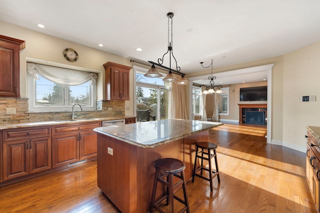 kitchen with a breakfast bar, a center island, sink, tasteful backsplash, and light stone counters