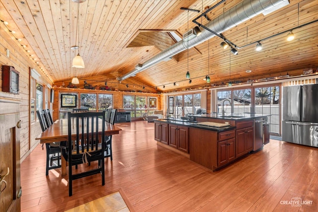 interior space with hardwood / wood-style floors, wooden ceiling, a center island with sink, hanging light fixtures, and appliances with stainless steel finishes